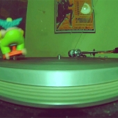 Homer Simpson dressed as Krusty, riding around on a turntable